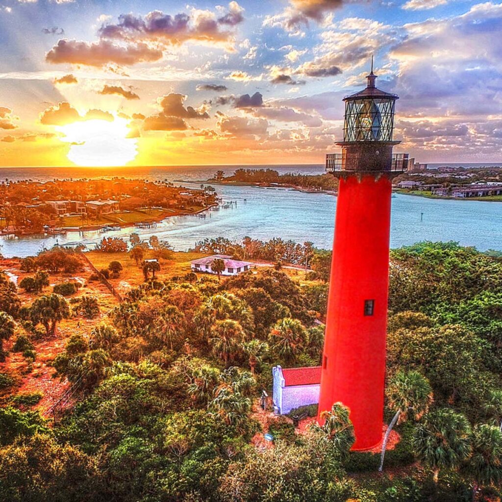 a red lighthouse near an inlet at sunset