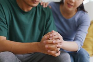 a person holds another's clasped hands and shows family support