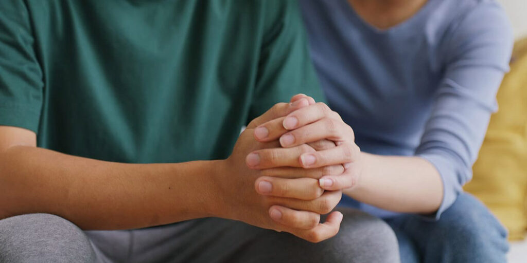 a person holds another's clasped hands and shows family support