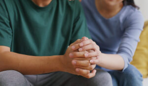 a person holds another's clasped hands and shows family support