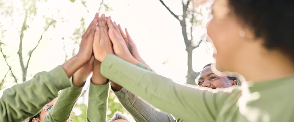 a group of people hold their hands to a point in the middle after learning about our vision