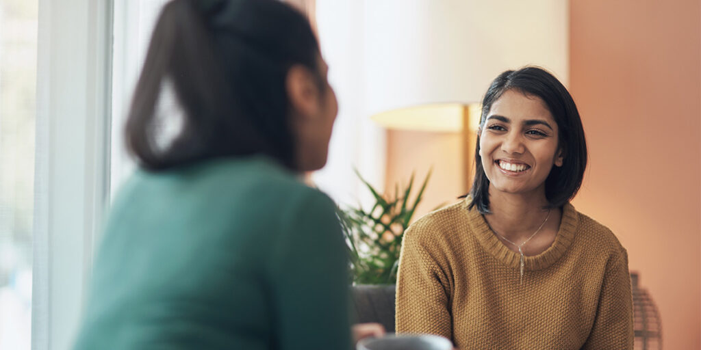 a person in long-term recovery smiles while listening to someone speak