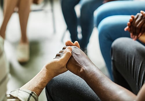 a 12-step approach group sits with their hands held