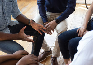 a group of people sit in a circle during an addiction treatment program