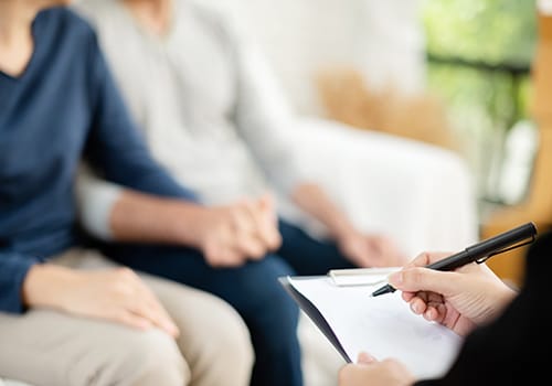 a couple holds hands while a therapist takes notes after they found family support and resources